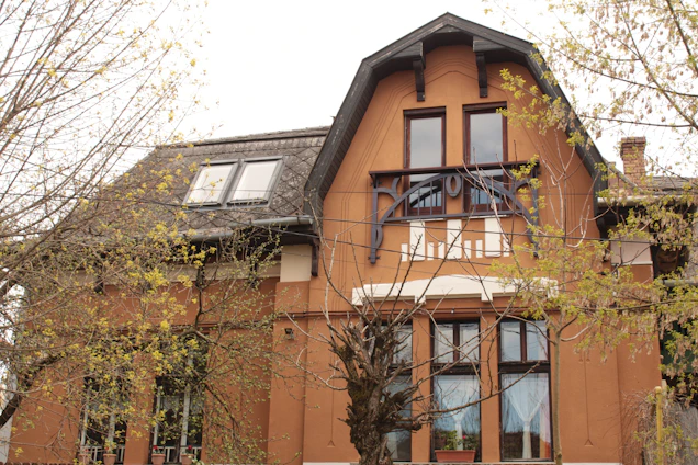 A skilled painter carefully applying a rich whitetail brown coat to the exterior of a cozy home nestled among trees.