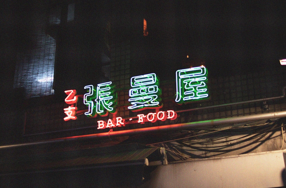 a neon sign that says bar - food on a building