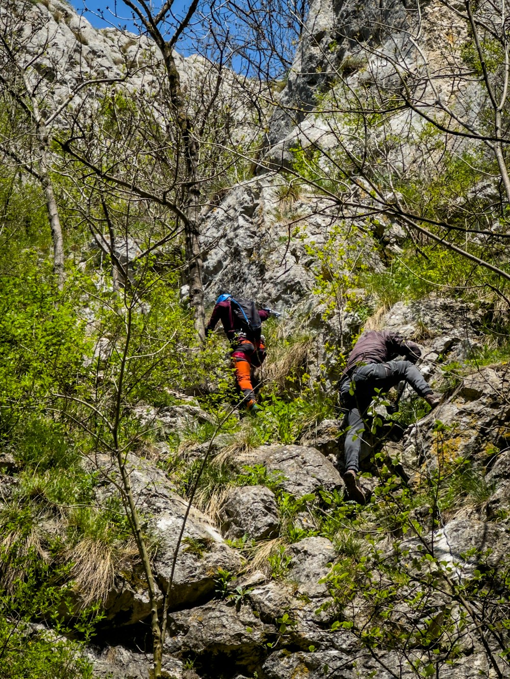 a couple of people climbing up a rocky hill