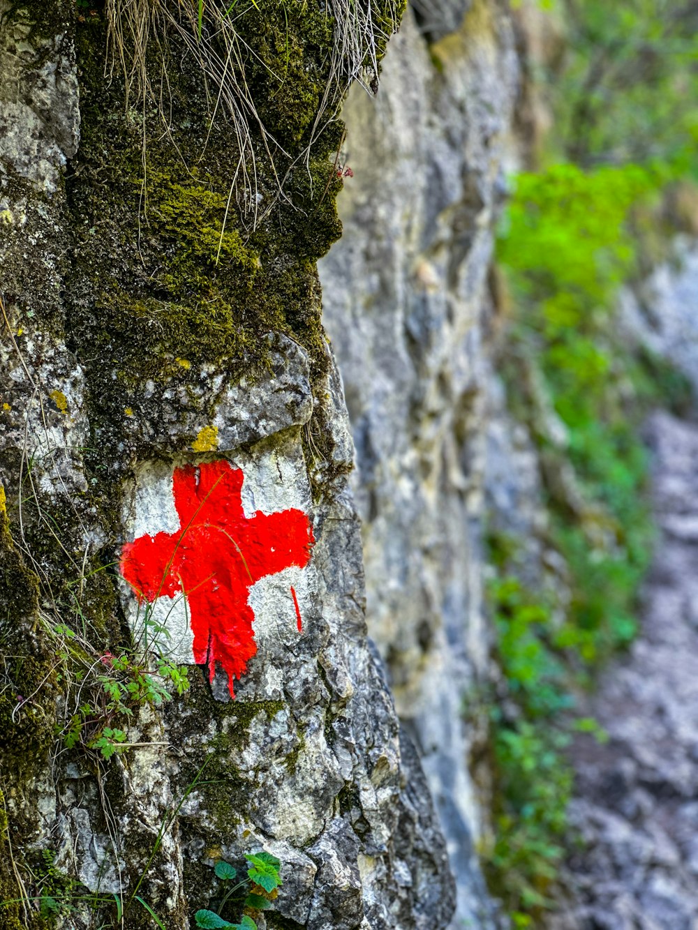 a red and white cross painted on a rock