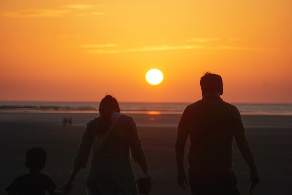 a man and a woman holding hands as the sun sets