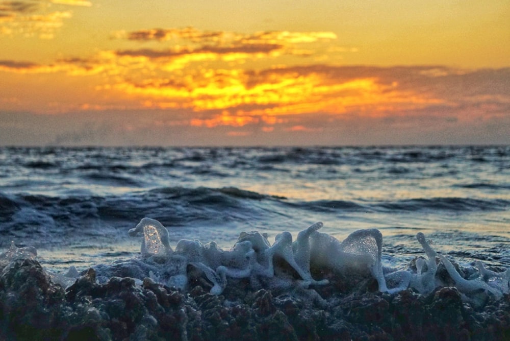 the sun is setting over the ocean with waves