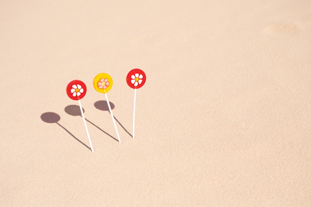 a group of three lollipops sitting on top of a sandy beach