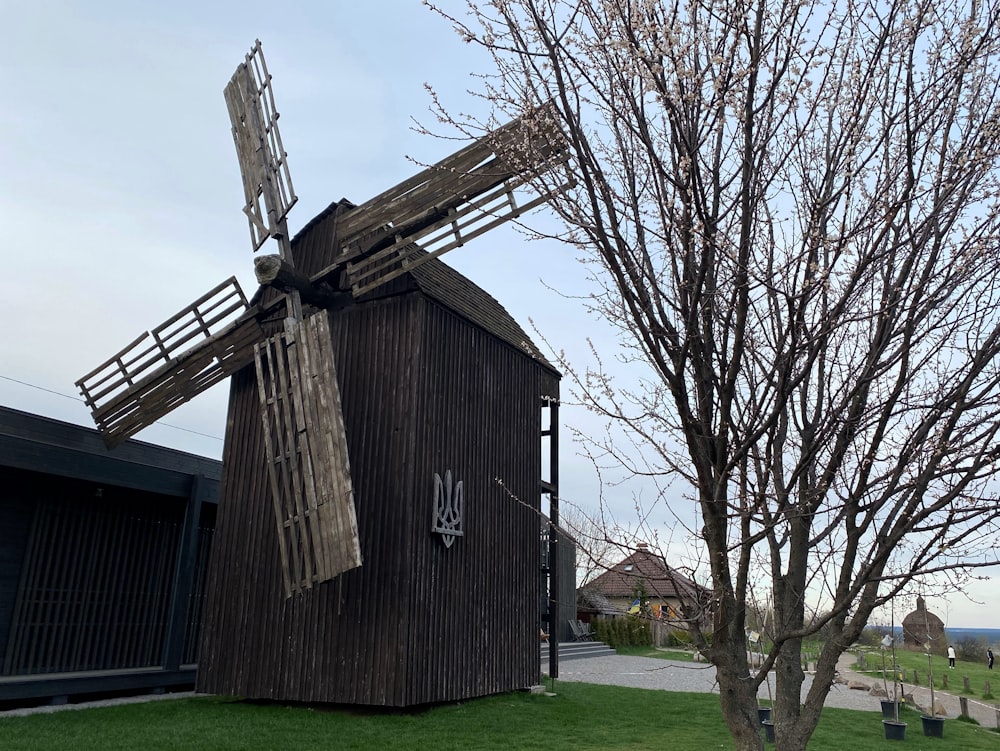 a windmill sitting next to a tree in a field