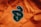 A close-up view of an orange corduroy fabric with a large black and green embroidered patch featuring the number 3. The texture of the fabric is visible, and the patch is prominently centered.