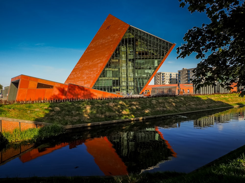 a building with a large orange triangle next to a body of water