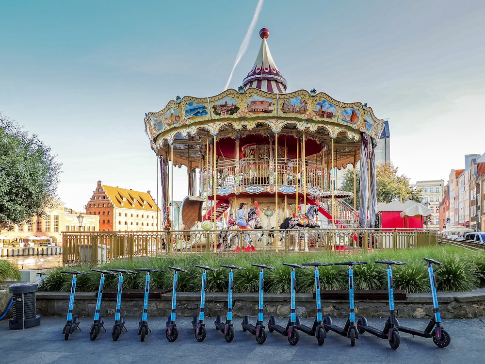 a row of scooters parked in front of a carousel