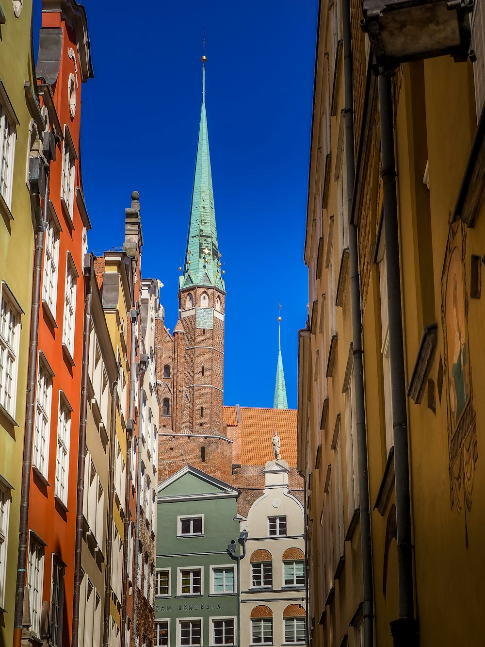 a narrow city street with a church steeple in the background