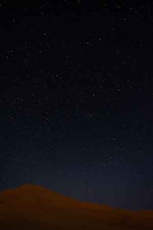 the night sky with stars above a sand dune