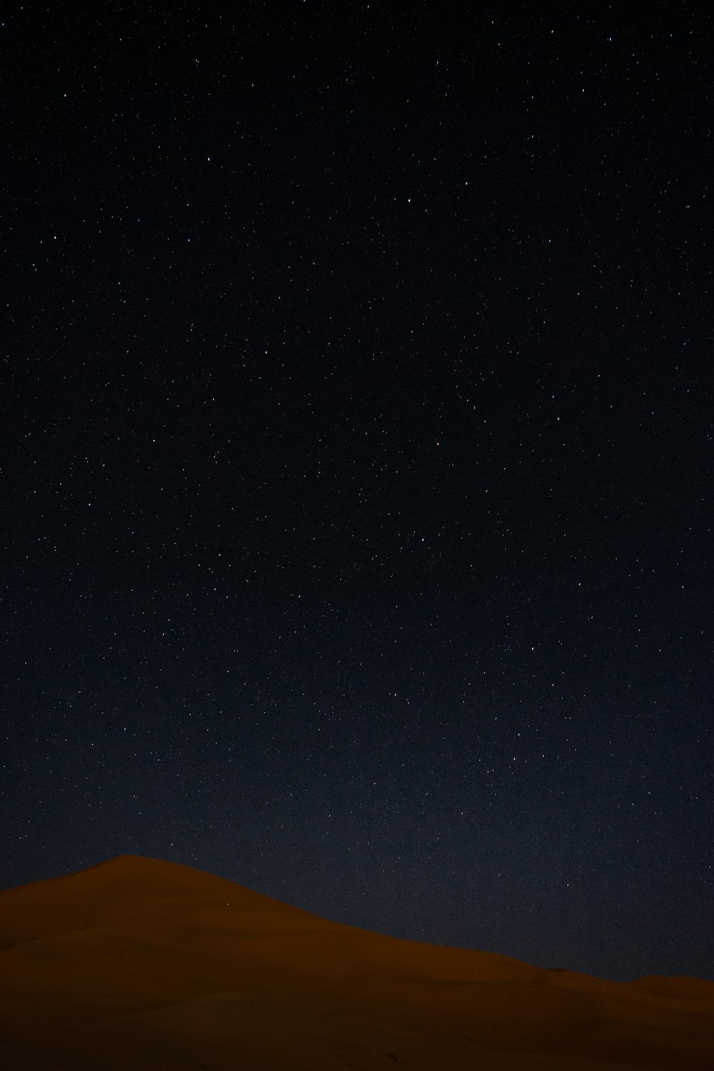 the night sky with stars above a sand dune