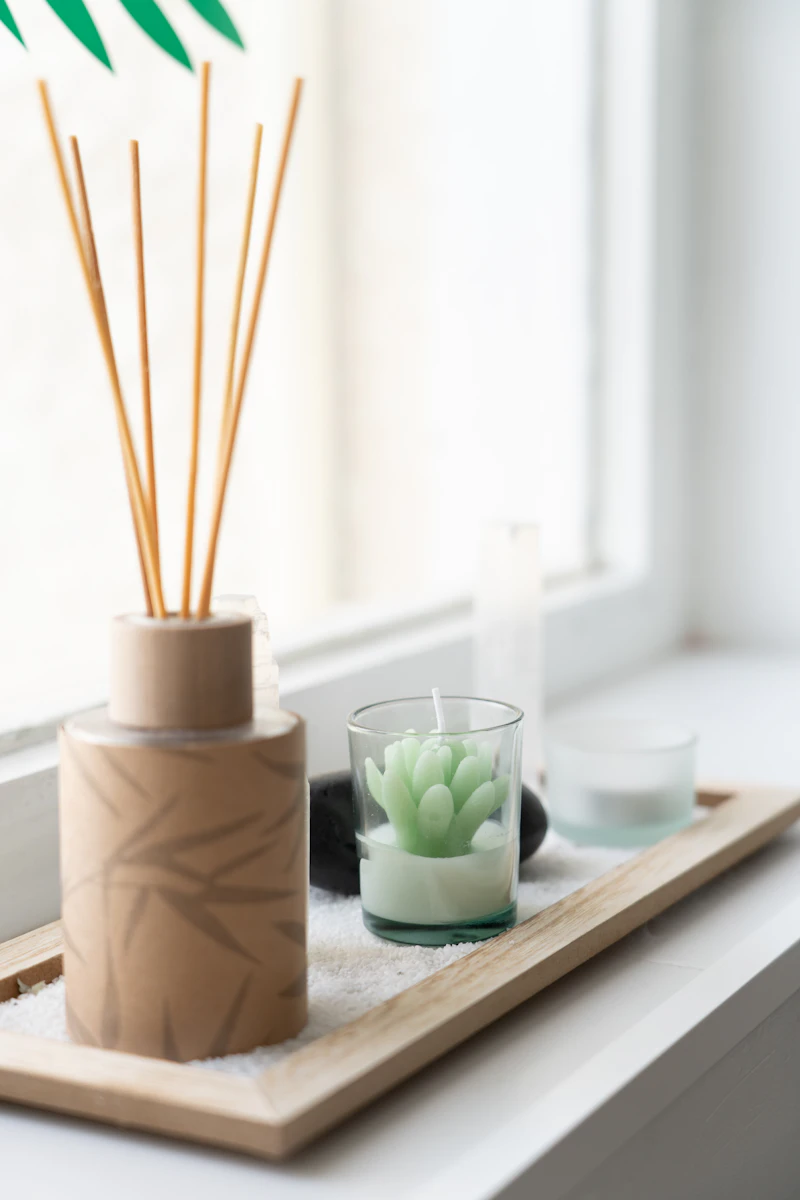 A reed diffuser and a candle in soft evening light