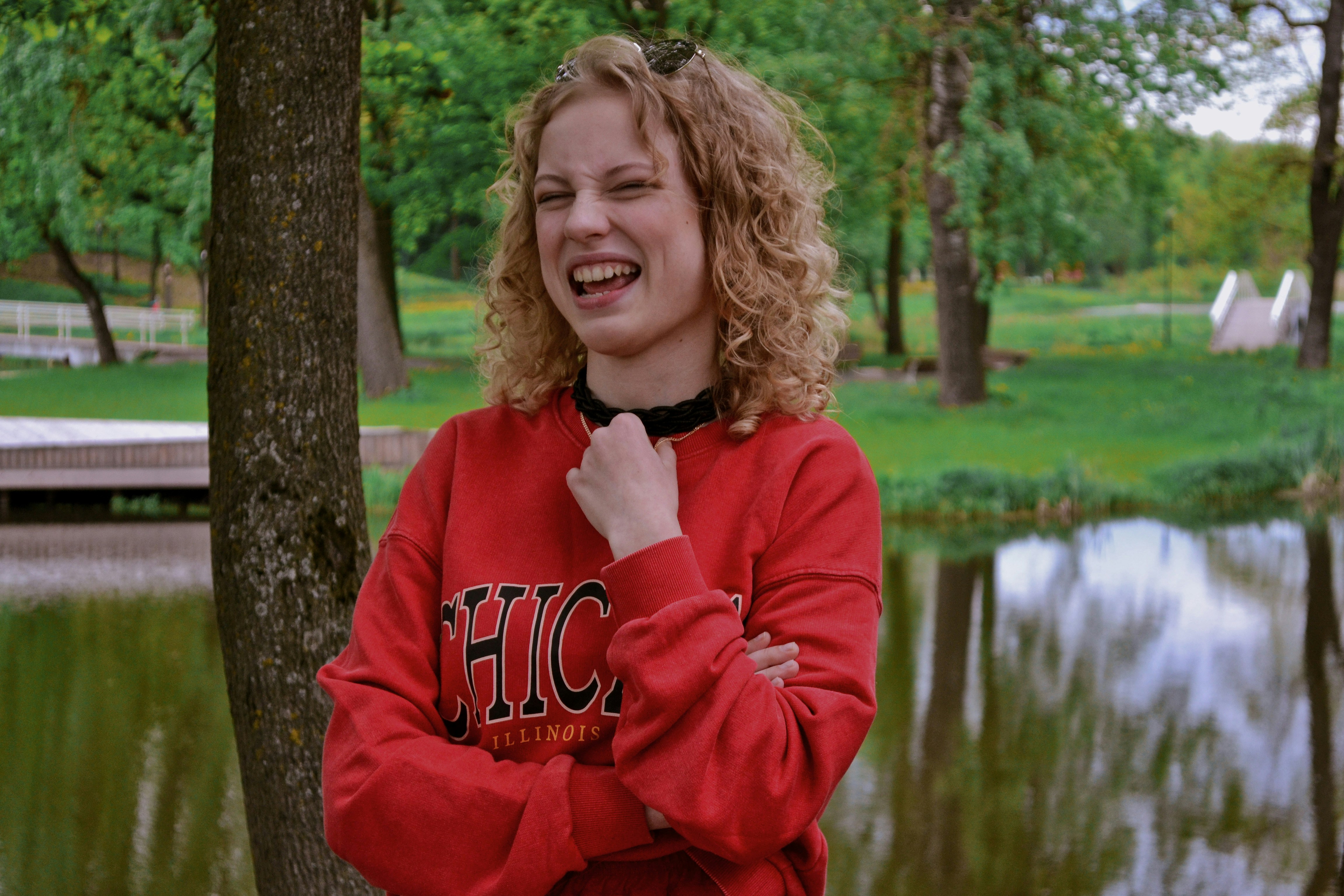 a woman in a red sweatshirt standing next to a lake