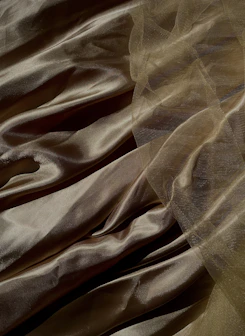 Luxurious silk salwar suit shimmering under soft light, showcasing rich textures in warm cream and gold.