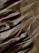 Silky fabric in a golden hue is draped and layered with soft, gentle folds. The surface has a subtle sheen, reflecting light across its smooth texture. A delicate mesh overlay adds depth, creating intricate patterns and enhancing the visual interest.