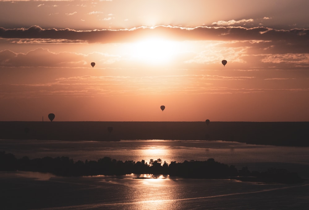 a group of hot air balloons flying over a lake
