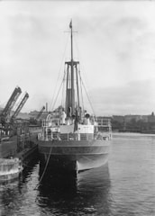 A large ship docked, with surveyors inspecting the vessel.