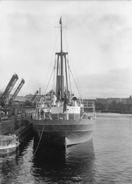 A large ship docked, with surveyors inspecting the vessel.