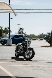 A busy car parking lot with motorcycles and bicycles neatly arranged under a clear sky.