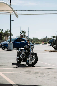 Motorcycle being carefully loaded onto a tow truck under a clear blue sky.
