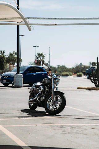 A busy car parking lot with motorcycles and bicycles neatly arranged under a clear sky.