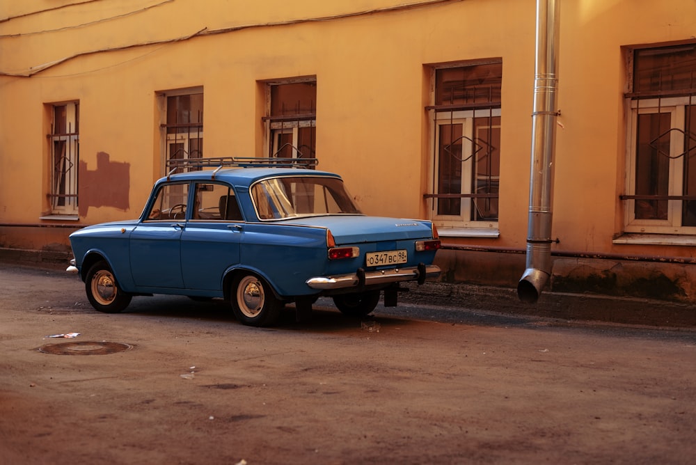 an old blue car parked in front of a building