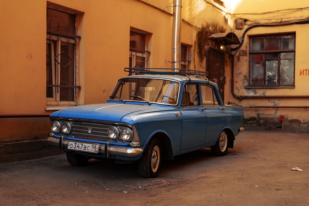 an old blue car parked in front of a building