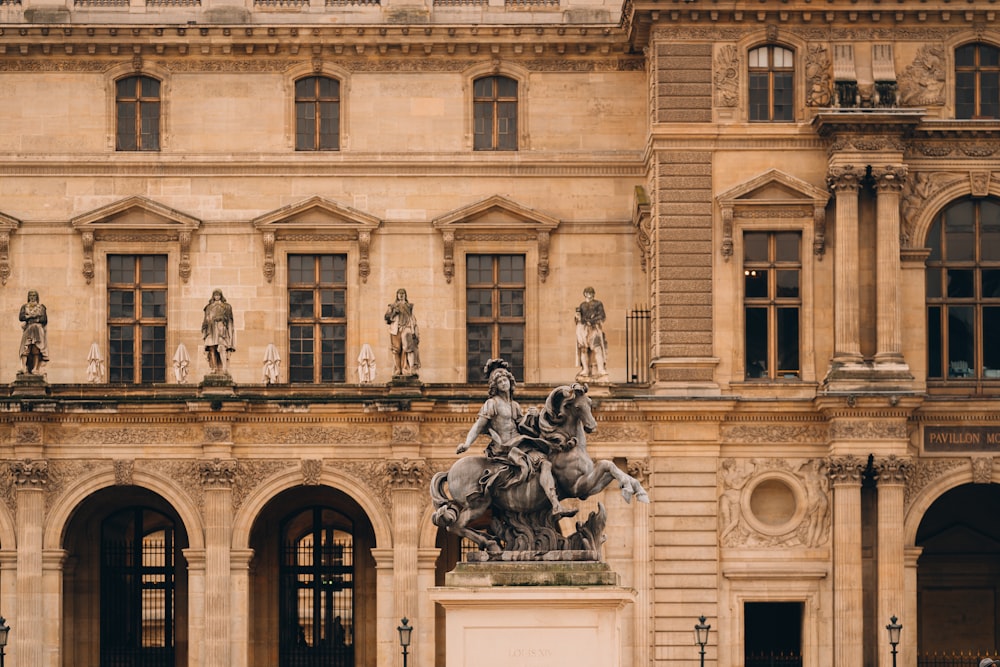 a statue of a man riding a horse in front of a building