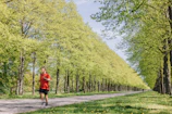 A cheerful runner jogging along a tree-lined trail under a bright blue sky.