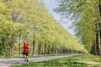 A cheerful person jogging in a sunny park surrounded by green trees.