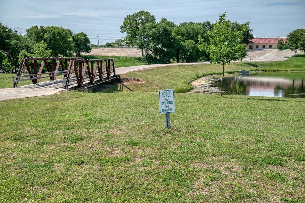 a sign is in the grass near a bridge