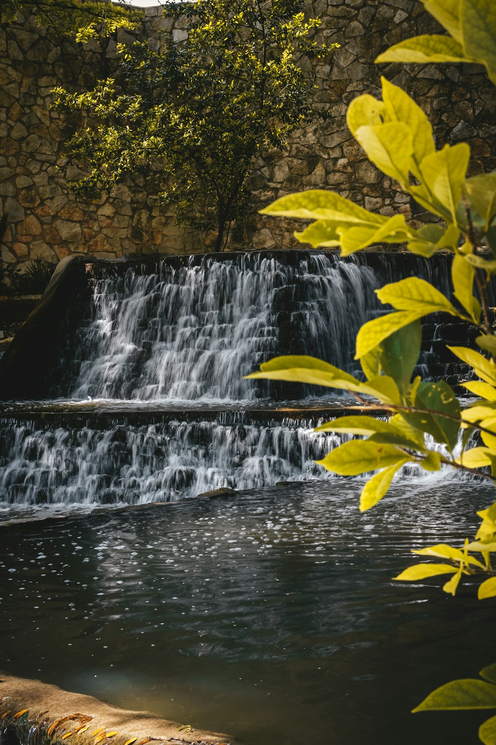 a small waterfall in the middle of a pond