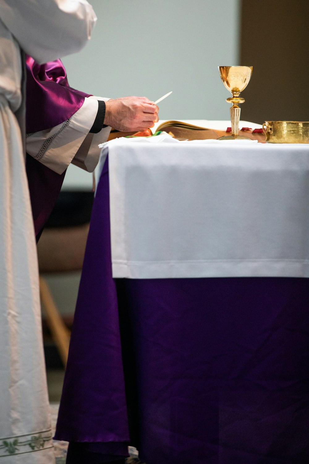 Ein Priester schreibt an einem Tisch auf ein Papier