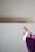 A person wearing a purple robe holds up a gold chalice against a plain background.