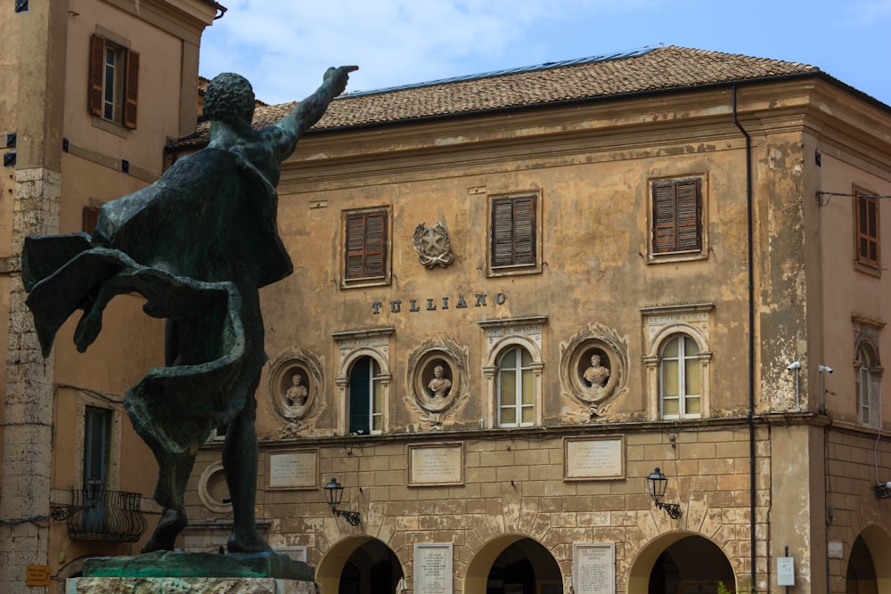 a statue of a man holding a fish in front of a building