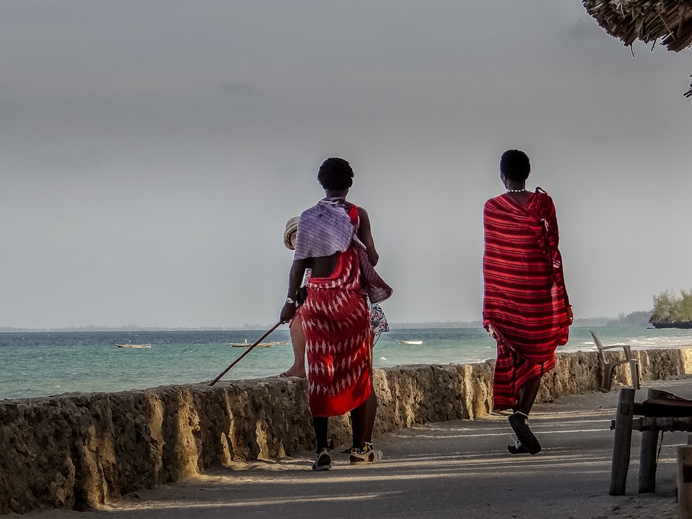 a couple of women walking down a street next to the ocean