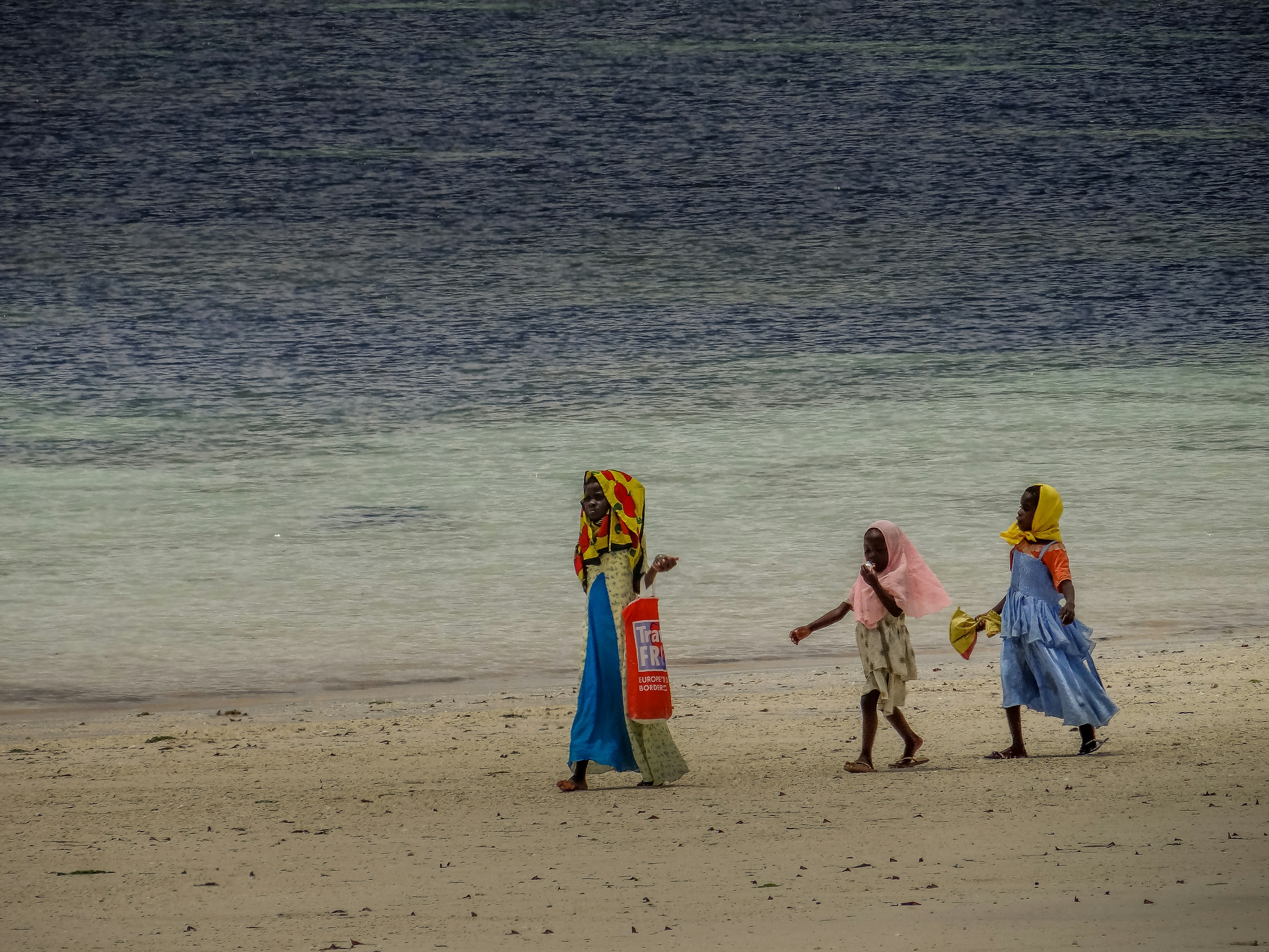 Tres mujeres caminando en una playa cerca del océano