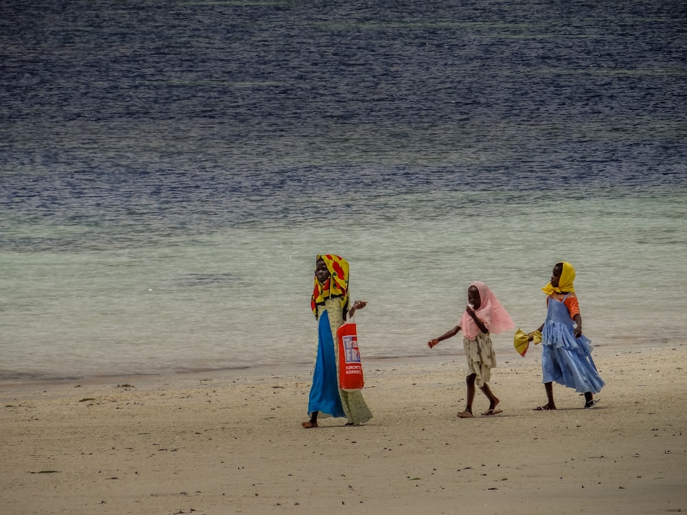 three women walking on a beach near the ocean