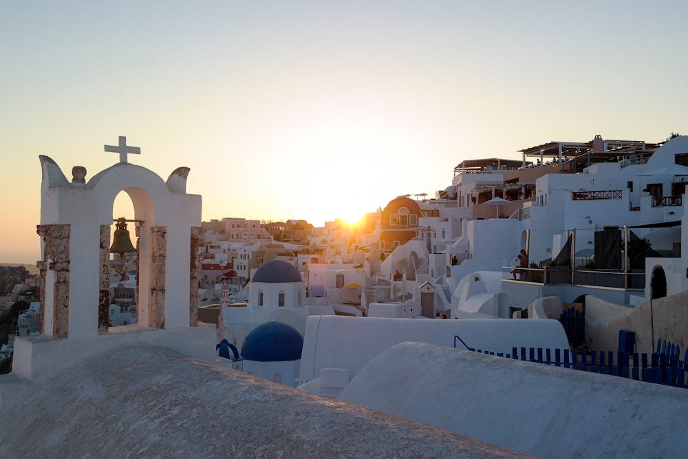 the sun is setting over a city with white buildings