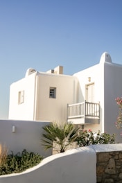 a white building with a balcony next to a palm tree