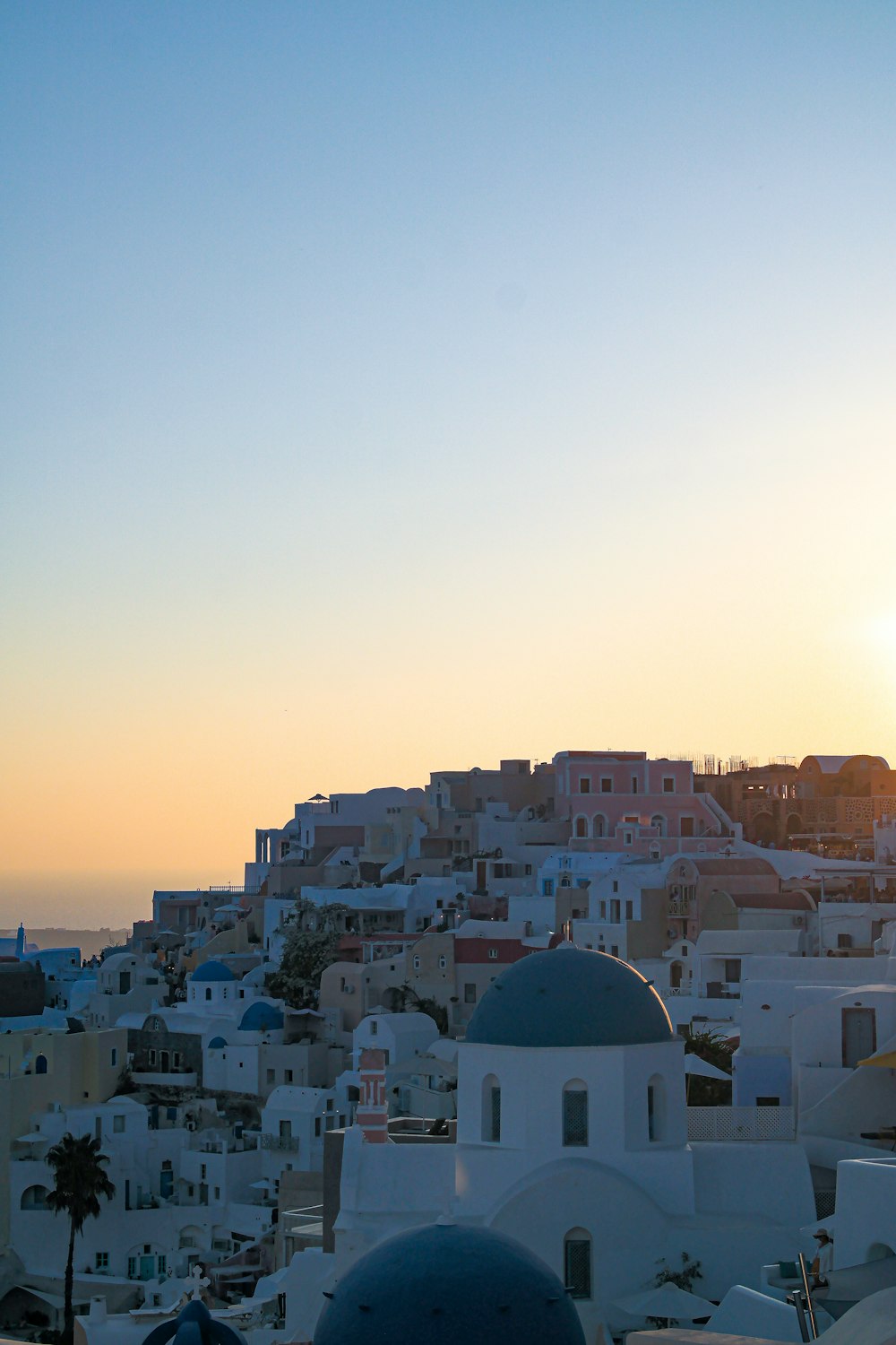 the sun is setting over a city with white buildings