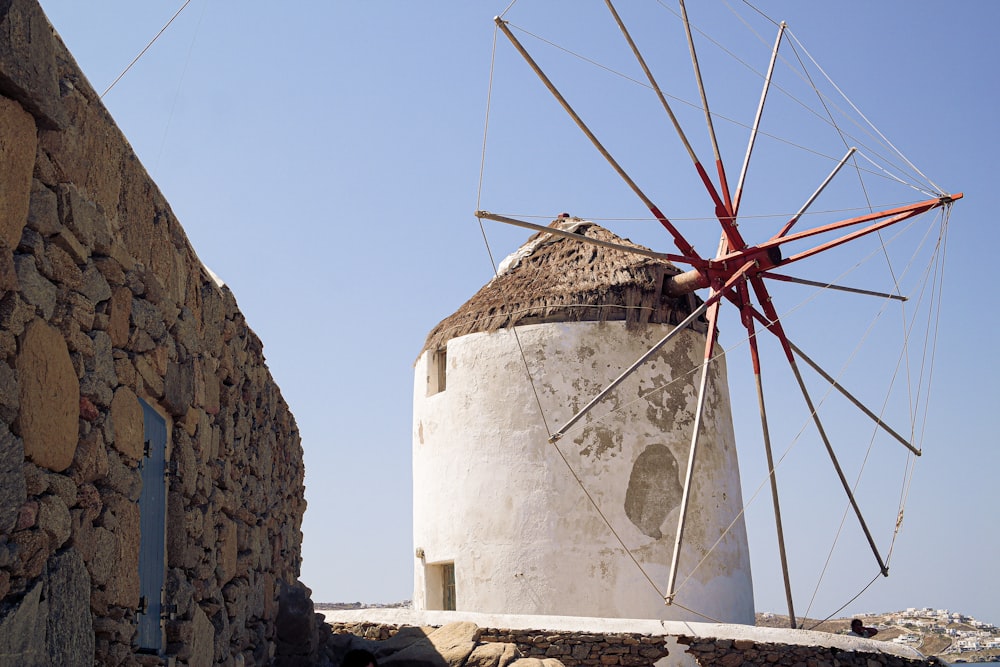 a white and red windmill next to a stone wall