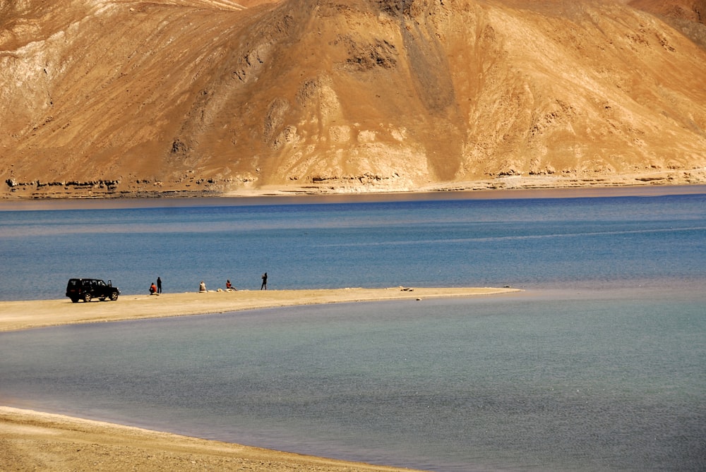 a group of people standing on a beach next to a body of water