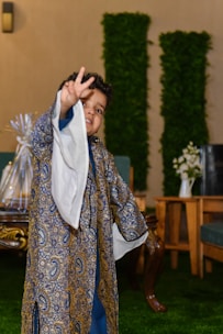 a little boy dressed in a blue and gold outfit