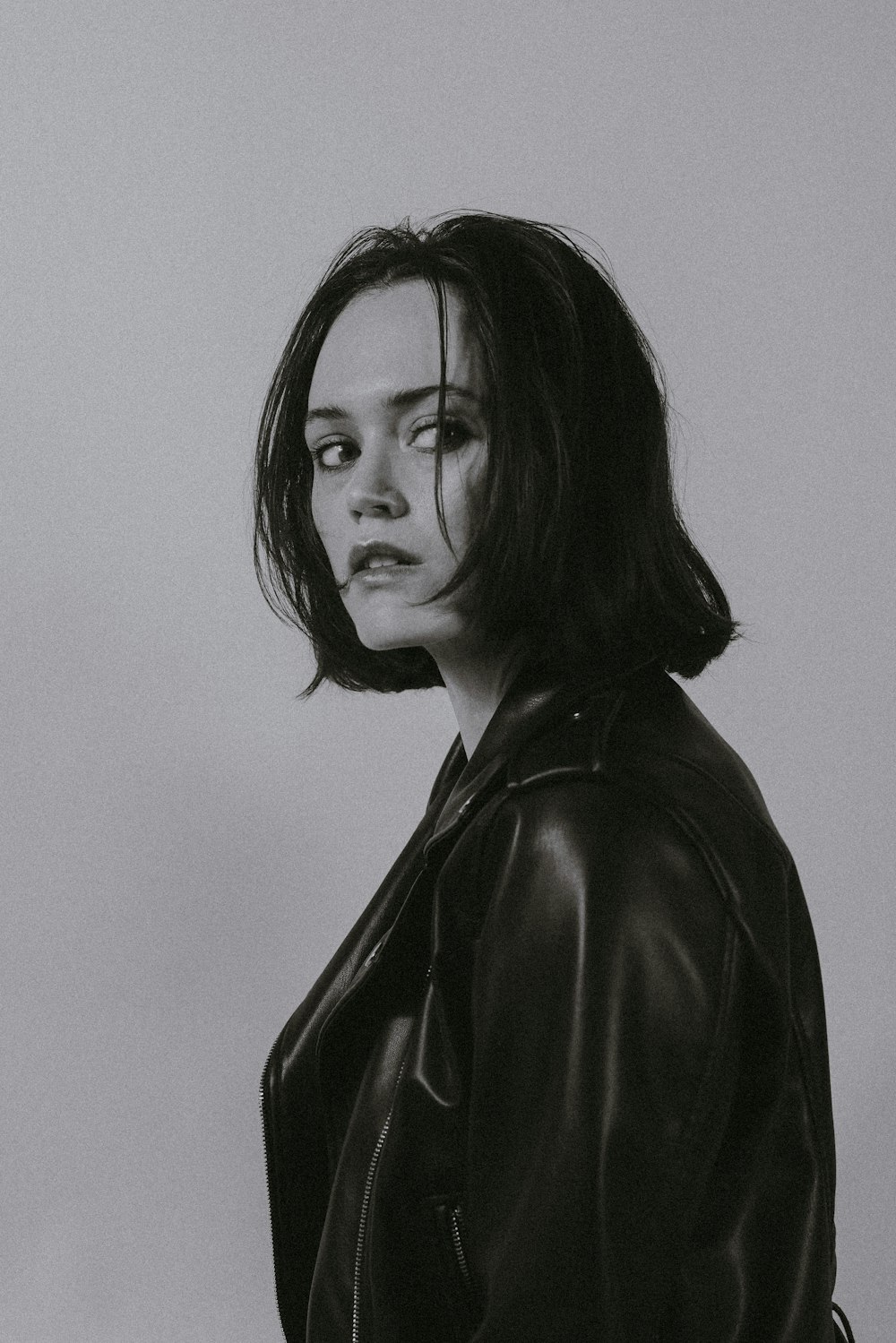 a black and white photo of a woman in a leather jacket