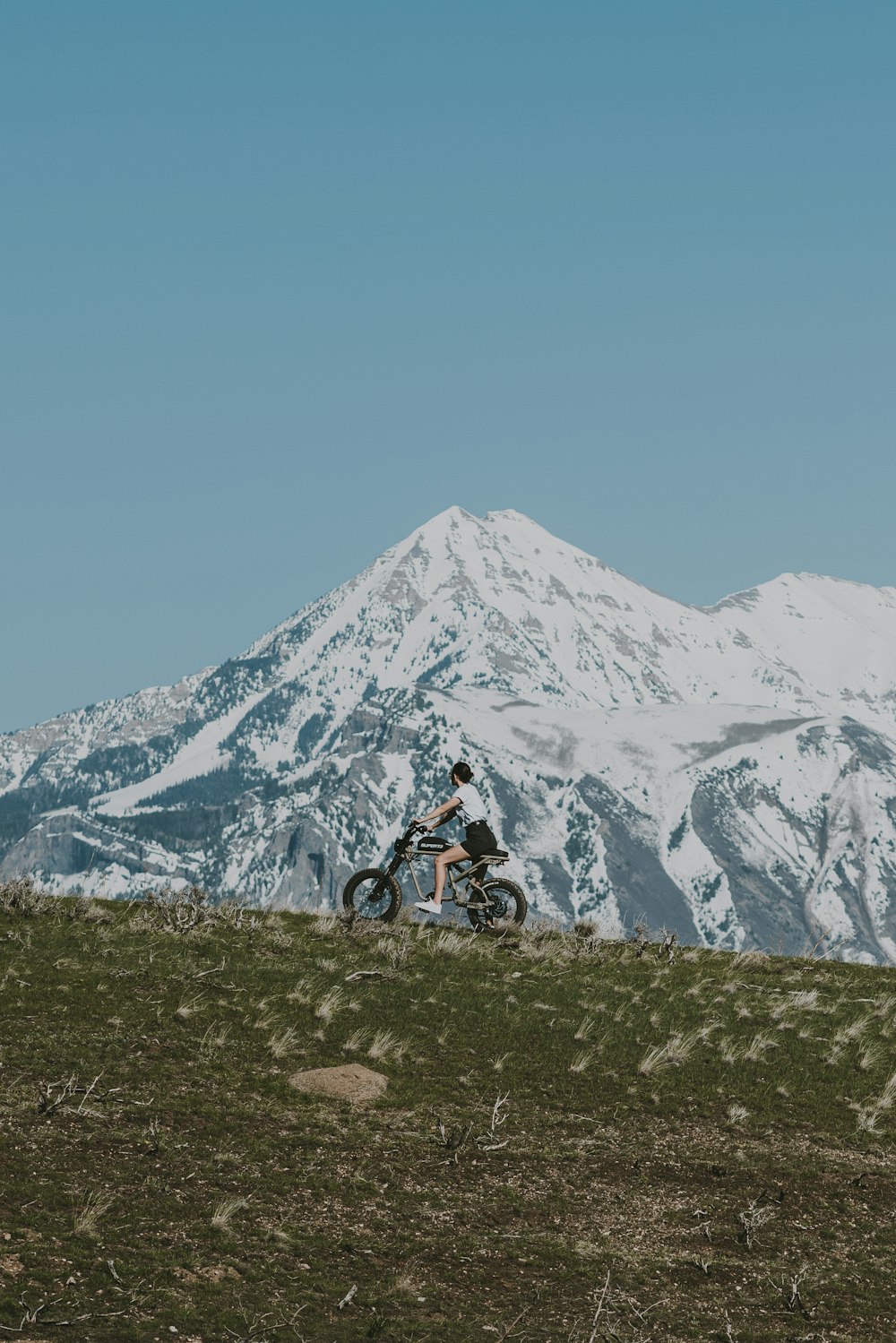 a man riding a motorcycle on top of a grass covered hill