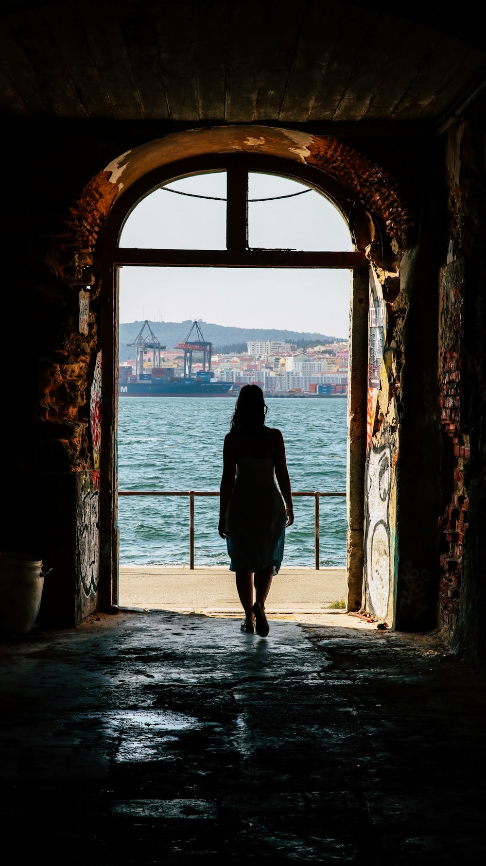 a woman walking out of a tunnel into the ocean
