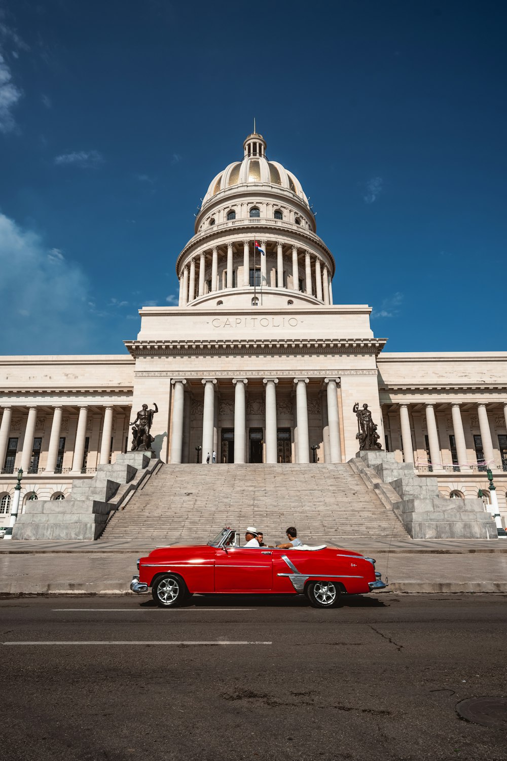 a red convertible car parked in front of the capitol building