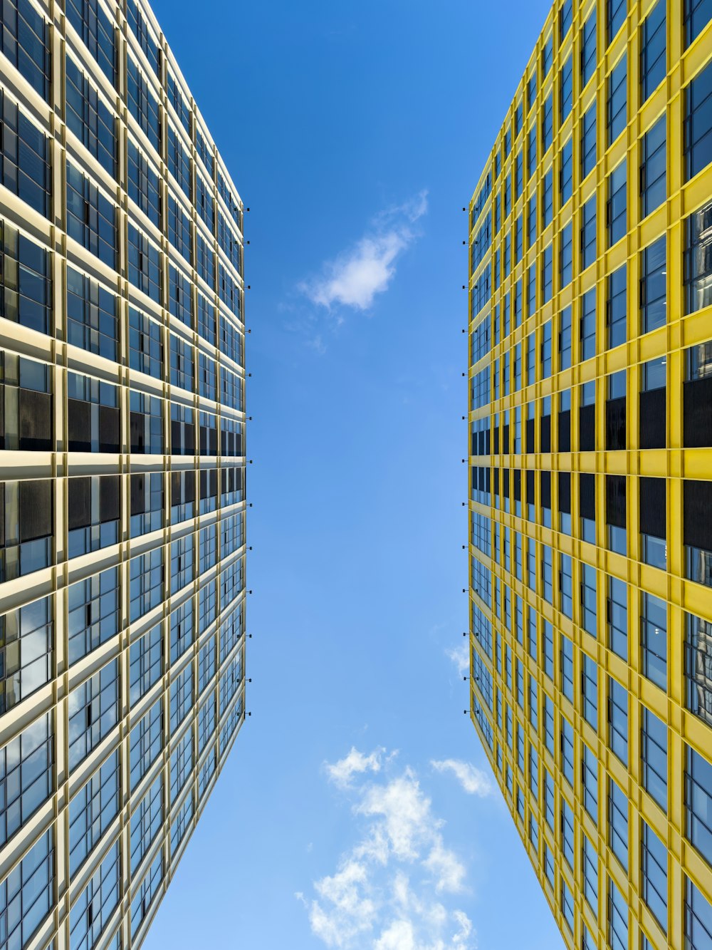 two tall buildings with windows and a blue sky in the background
