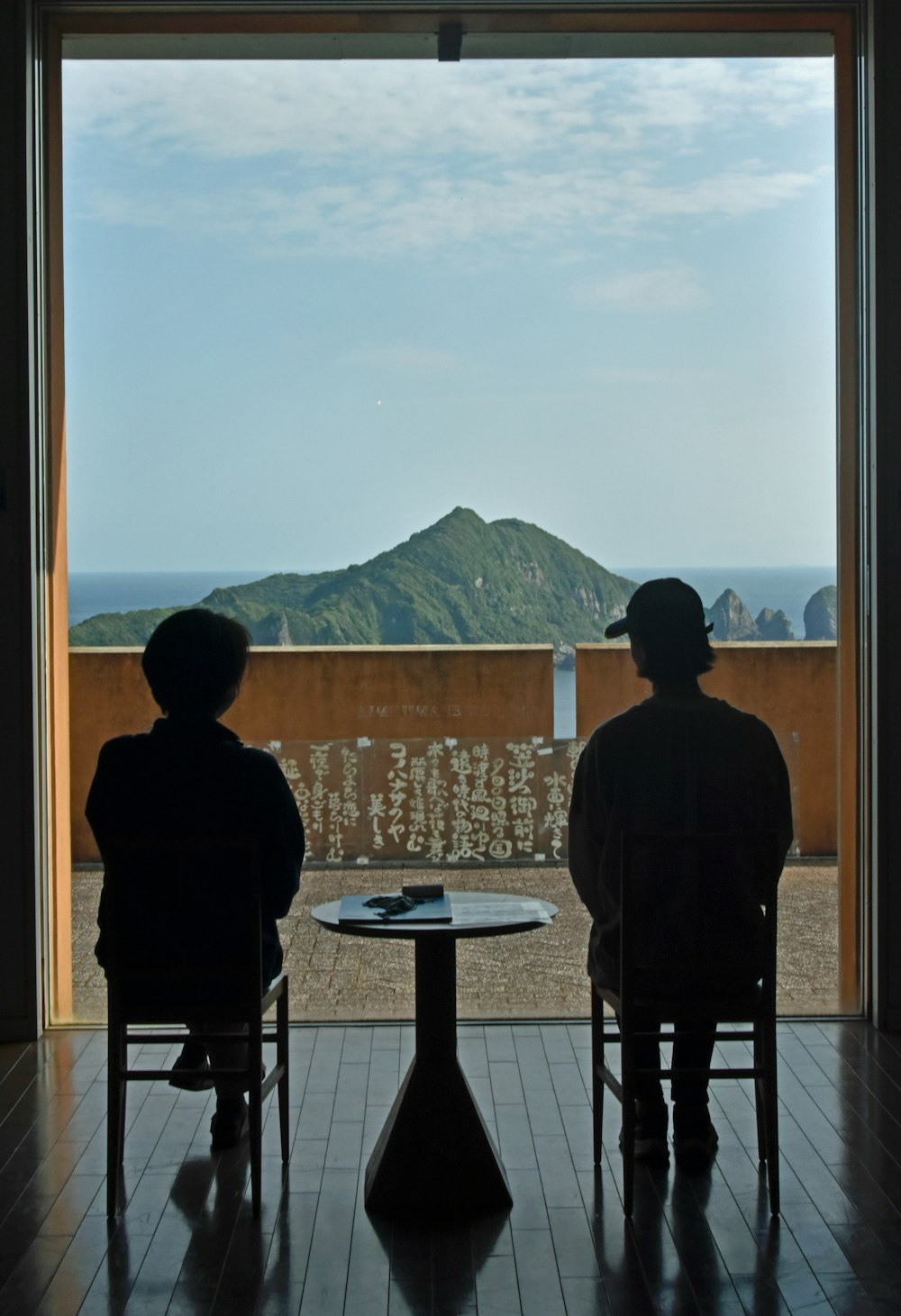 two people sitting at a table looking out a window