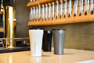 An assortment of travel mugs in various designs on display.